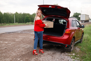 girl puts the box in the trunk
