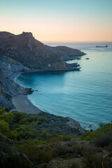 Fototapeta premium Vertical view from above of the stunning Fatares beach in Cartagena, Murcia Region, Spain, in summer with sunrise light