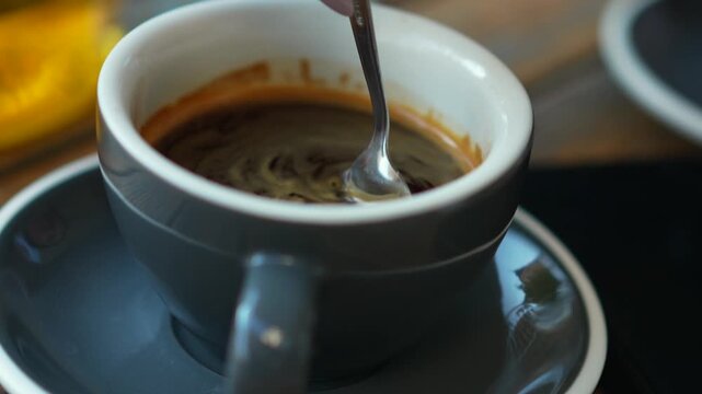 a woman's hand stirs coffee in a cup.
Americano big pan.
Fragrant coffee.
Cup of coffee.
Hot coffee in a cup