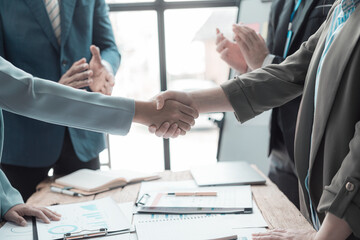 Businessmen holding hands having documents with graphs and financial charts, concept of business agreement together, close-up image.