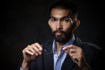 Portrait, A bearded man wearing glasses and black suit poses in the studio.