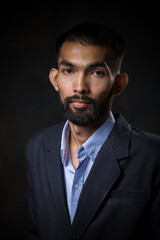 Portrait of bearded handsome man in black suit in a pensive mood and looking at camera.