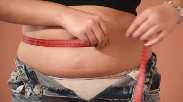 Woman measures waist circumference with measuring tape, diet and healthy lifestyle. Post-partum tummy Horizontal 4k footage	