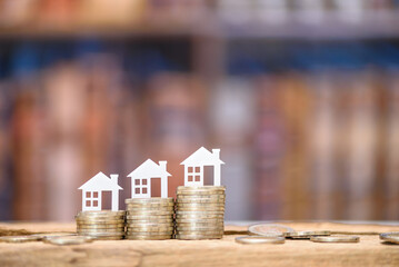 Mortgage loan or home equity loan, financial concept : Tiny model residential house perched atop coin stacks, depicting home loan or borrowing money to purchase a new home for first time homebuyer.