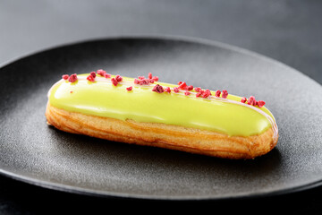 Beautiful french eclair with pistachio filling on a black plate