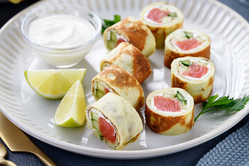 Homemade crepe rolls stuffed with salted salmon, cream cheese and fresh cucumber. Delicious appetizer.