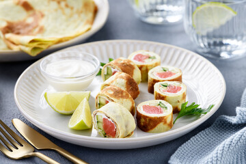 Homemade crepe rolls stuffed with salted salmon, cream cheese and fresh cucumber. Delicious appetizer.