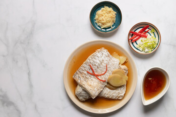 This dish is a steamed fish with ginger and scallions. It is served with a dipping sauce.