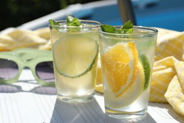 Tasty cocktail in glasses and sunglasses near swimming pool outdoors