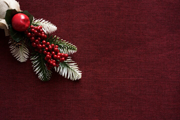 Flat lay background for holiday and new year greeting card. Photo with red brown white green christmas tree decoration placed on a red colored jute fabric with a customized layout to place the text