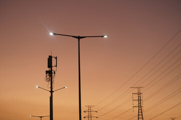 Evening sky sunset at the edge of a city street under a street lamp and a power tower in the...
