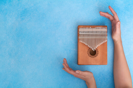 Female hands with a kalimba on a blue background