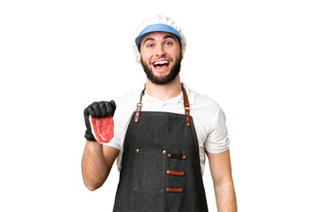 Butcher man wearing an apron and serving fresh cut meat over isolated chroma key background with surprise facial expression