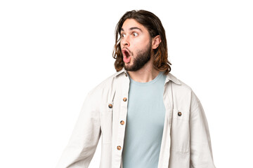 Young handsome man over isolated chroma key background doing surprise gesture while looking to the side