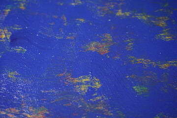 Mixed rough paint splatter on a textured blue paint surface, Grungy colorful paint brush strokes backdrop, Abstract multicolor paint splash background