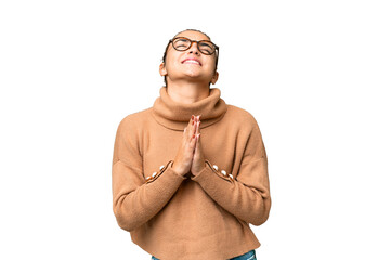 Young beauty woman over isolated chroma key background keeps palm together. Person asks for...