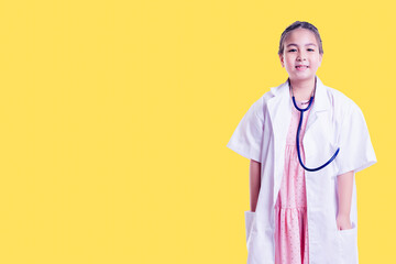 Young girl smiles while wearing a white lab coat and stethoscope, embodying the role of a doctor. Stand against yellow background ideal for concepts related to childhood dreams, healthcare, education