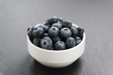 ripe blueberries in white bowl on slate background