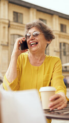 A Joyful Senior Woman Happily Enjoying Her Coffee While Engaging in Cheerful Conversation