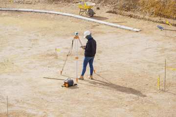 A man is standing in a field with a surveying instrument