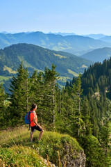 pretty senior woman hiking in warm dawn sunlight and enjoying the spectacular view over the Allgau alps on the Nagelfluh mountain chain near Oberstaufen, Bavaria, Germany