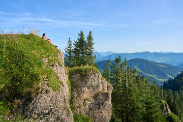 pretty senior woman hiking in warm dawn sunlight and enjoying the spectacular view over the Allgau alps on the Nagelfluh mountain chain near Oberstaufen, Bavaria, Germany