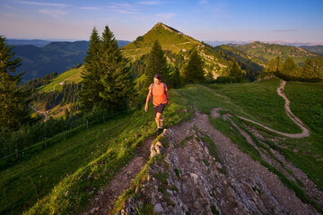 pretty senior woman hiking in warm dawn sunlight and enjoying the spectacular view over the Allgau...