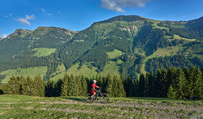 pretty senior woman riding her electric mountain bike and enjoying the spectacular view over the...