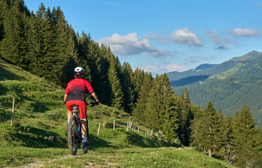 pretty senior woman riding her electric mountain bike and enjoying the spectacular view over the...