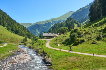 active senior woman riding her electric mountain bike in the spectacular Rappenalpen Valley south of Oberstdorf in the Allgaeu High Alps, Bavaria, Germany