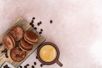 Cup of coffee and chocolate macaroons with coffee beans on wooden board. Top view with copy space