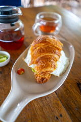 Savor a delectable breakfast featuring a croissant paired with a delightful cup of tea