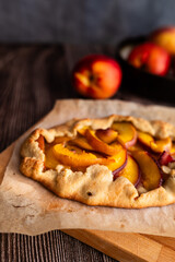 Homemade nectarine galette on dark wooden background, close up, place for text, top view