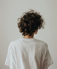 Young man with curly hair wearing a white shirt indoors at home