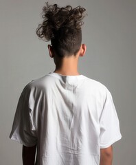 Obraz premium Young man with curly hair facing away in minimalist studio setting