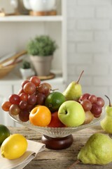Glass vase with different fresh fruits on wooden table