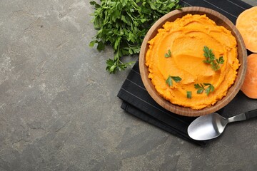 Delicious mashed sweet potatoes with parsley served on gray textured table, flat lay. Space for text