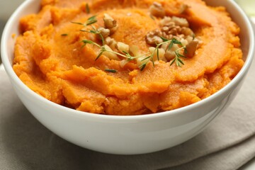 Delicious mashed sweet potatoes and nuts in bowl on table, closeup