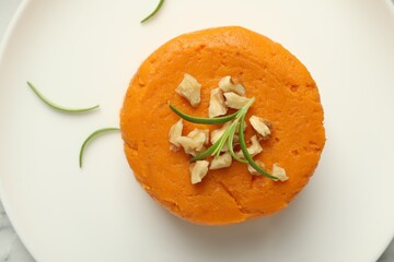 Tasty mashed sweet potato, rosemary and walnuts on plate, top view