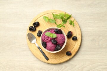 Delicious blackberry sorbet with fresh berries in bowl and spoon on table, top view