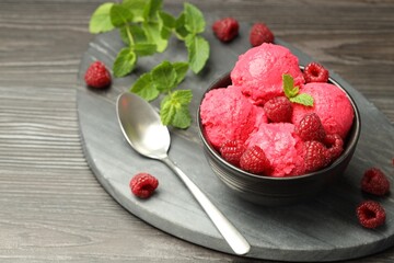 Delicious raspberry sorbet in bowl, fresh berries, mint and spoon on wooden table, closeup