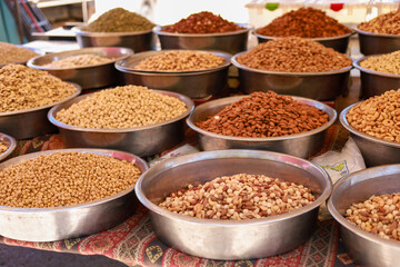Many different nuts in large metal vices on the counter of a local bazaar