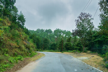 Cloudy sky and curve of Himalayan road, monsoon landscape of Garhwal, Uttarakhand, India. Climate change effect on Himalays bringing landslide, untimely rain and destruction of mountain environment.