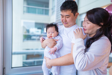 Obraz premium family of three, a man and two women, are hugging a baby