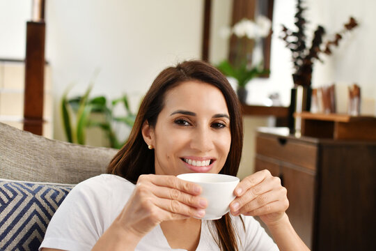 Chica bonita sonriendo a la c&aacute;mara mientras toma una deliciosa taza de caf&eacute; caliente por la ma&ntilde;ana. Toma horizontal.
