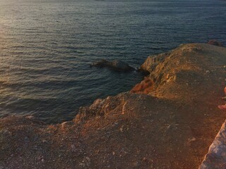 Serene Sunset Over a Rocky Coastline with Gentle Waves and Golden Evening Light