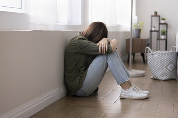 Teen girl crying seated on floor, suffers from bullying, pressure or intimidation from peers at...