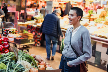hispanic young woman with skinhead or short hair shopping vegetables and fruits on traditional market or grocery	