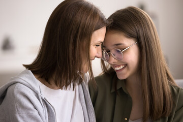 Close up happy mature mother sit on sofa with teenage 16s daughter, show care, enjoy moment of tenderness. Different generations family express support and unconditional love. Understanding and ties