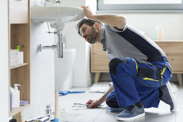 Professional repairman checking a leaking bathroom sink